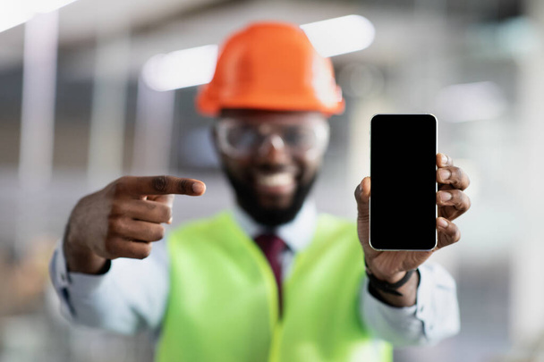 Smiling african american civil engineer showing smartphone with empty screen - Photo, Image