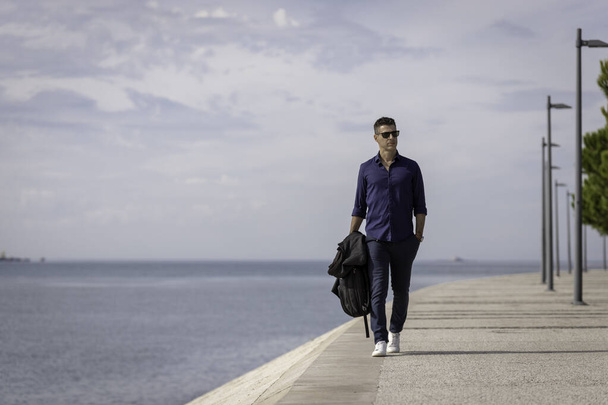 Портрет молодого класичного підприємця, що відпочиває на самоті вздовж річки Лісабон у Португалії. Класичний бізнесмен у блакитній елегантній сорочці і формальному одязі. Успішний спосіб життя. - Фото, зображення