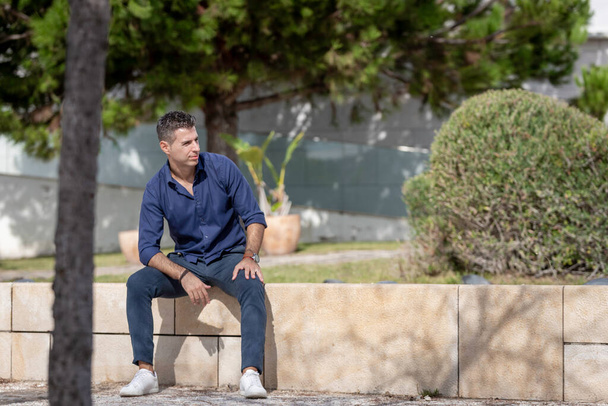 Portret młodego przedsiębiorcy z klasą, odpoczywającego samotnie nad brzegiem Lizbony w Portugalii. Elegancki biznesmen w niebieskiej, eleganckiej koszuli i formalnym stroju. Pomyślna koncepcja stylu życia. - Zdjęcie, obraz
