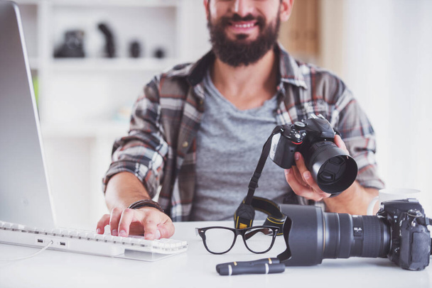 Young cheerful photographer with beard, while working in his office - Foto, imagen
