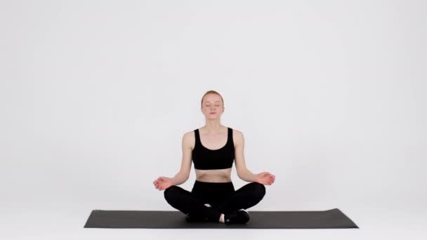 Yoga-Kurs. Friedliche junge Frau meditiert in Lotusposition im Atelier - Filmmaterial, Video