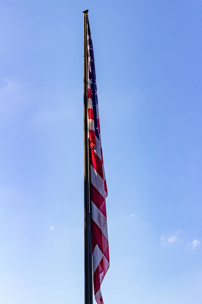 Закрыть вид американского флага в неподвижном воздухе на голубом фоне неба - Фото, изображение