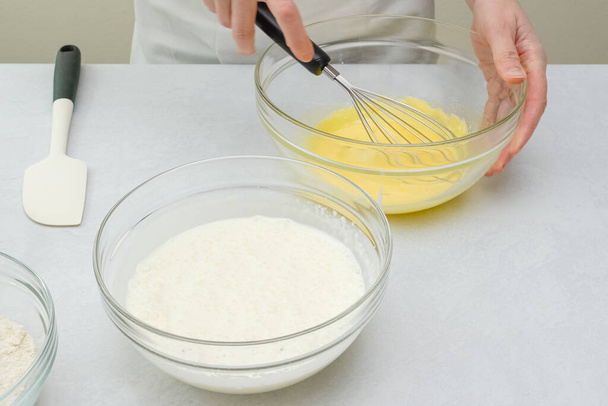 Whisked białka jaj i whisked żółtka jaj w szklanych misek zamknąć na stole kuchennym. Proces pieczenia, krok po kroku przepis ciasto czekoladowe - Zdjęcie, obraz