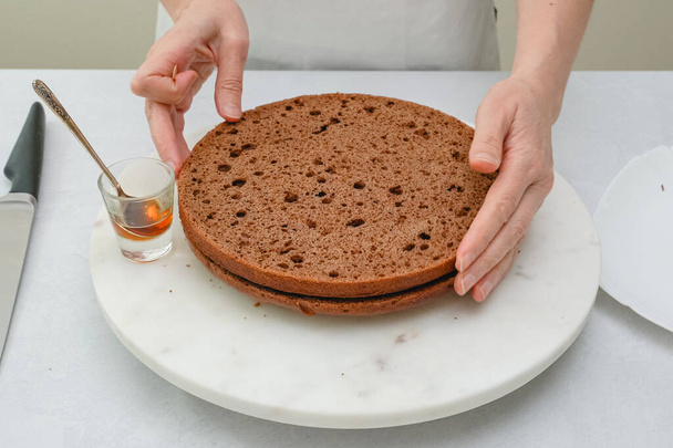 Rum-Sauce über Schokoladenkuchen gießen. Schritt für Schritt Schokoladenkuchen mit Schokoladencreme Zuckerguss Rezept - Foto, Bild