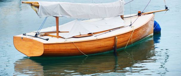 Een elegante oude gaff opgetuigd klassieke boot verankerd op ligplaats in de buurt van de kust van de oceaan, close-up. Bretagne, Frankrijk. Vervoer, zeilen, racen, regatta, sport en vrijetijdsbesteding, vakantie, cruise - Foto, afbeelding