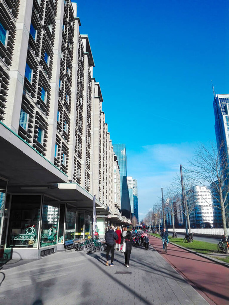 ROTTERDAM, NETHERLANDS - Feb 20, 2019: A group of people walking on a sidewalk next to companies and an apartment building in the city center. - Foto, imagen