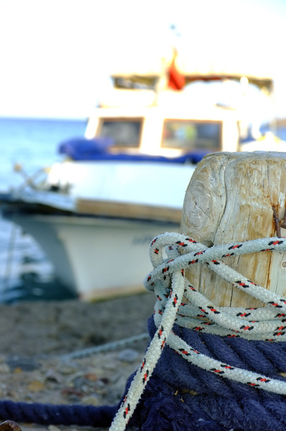 Pequeño barco de pesca amarrado a poste de madera
 - Foto, Imagen
