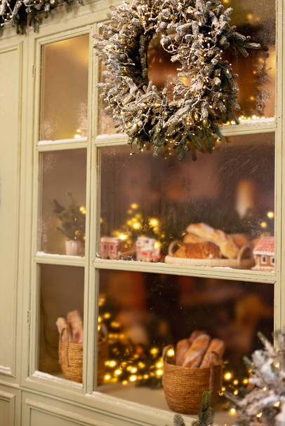 A hófödte ház díszített az új évre. Vintage téli udvar, karácsonyfákkal, lámpásokkal és friss süteményekkel díszített kirakattal. Puha szelektív fókusz. - Fotó, kép