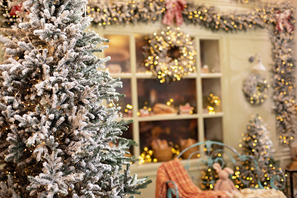 Karla kaplı ev yeni yıl için dekore edildi. Noel ağaçları, fenerler, rahat bir bank ve taze hamur işleriyle süslenmiş klasik kış avlusu. Yumuşak seçici odak. - Fotoğraf, Görsel