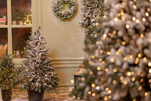 Das schneebedeckte Haus ist für das neue Jahr dekoriert. Vintage-Winterhof, dekoriert mit Neujahrsschmuck, Weihnachtsbäumen, Laternen Lichter. Weiche selektive Fokussierung. - Foto, Bild