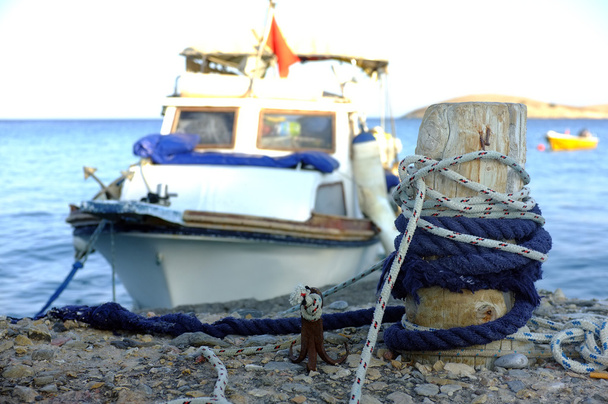 Pequeno barco de pesca amarrado ao poste de madeira
 - Foto, Imagem