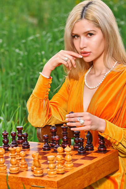 Woman plays chess in nature in the field - Photo, Image