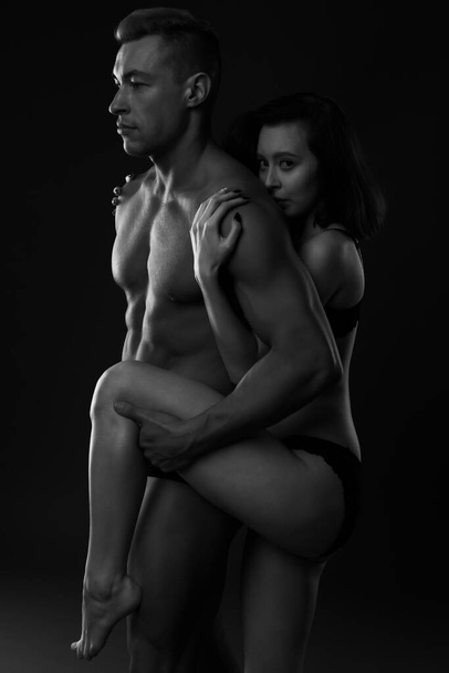 black and white photo of a passionate couple embracing on a dark background - Фото, изображение
