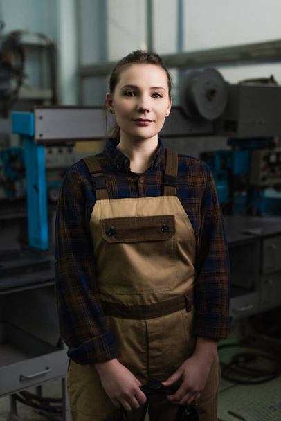 Young welder in overalls looking at camera in factory  - Foto, imagen