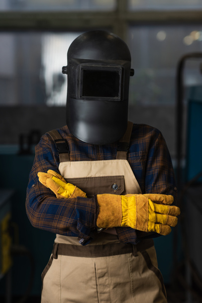 Saldatore in guanti, maschera protettiva e tuta in piedi in fabbrica  - Foto, immagini