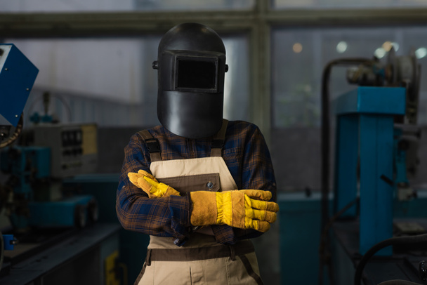 Soldador em capacete de proteção com viseira e luvas de pé na fábrica  - Foto, Imagem