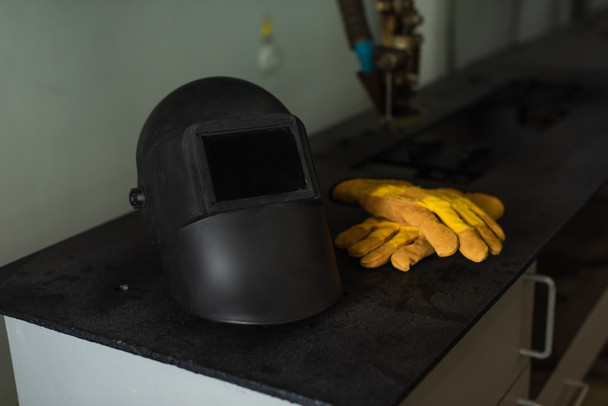 Máscara de soldadura y guantes en la mesa en fábrica  - Foto, Imagen