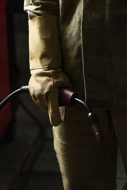Vista recortada de soldador en guante y antorcha de soldadura de retención uniforme en fábrica  - Foto, imagen