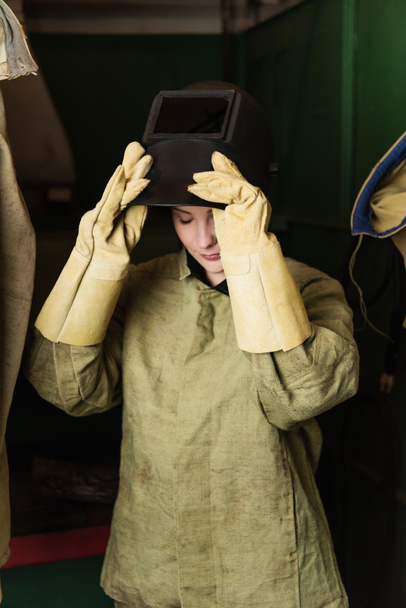 Soldador joven en guantes con máscara de soldadura en fábrica  - Foto, Imagen