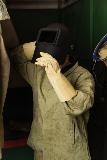 Soldador em luvas de proteção usando máscara de solda na fábrica  - Foto, Imagem