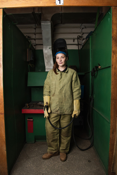 Mladý svářeč v uniformě držení svařovací hořák v továrně  - Fotografie, Obrázek