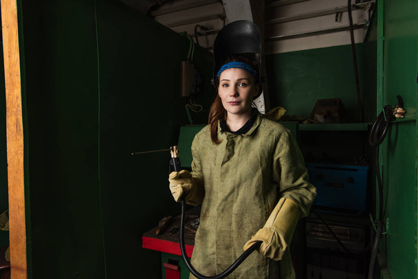 Young welder in uniform holding welding torch and looking at camera in factory  - Fotografie, Obrázek