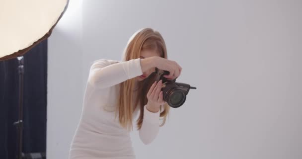 Φωτογράφος κορίτσι παίρνει φωτογραφίες στο στούντιο - Πλάνα, βίντεο