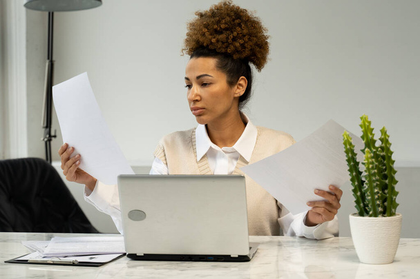 Злая афро-американская предпринимательница, у которой проблемы в офисе, держит офисные бумаги - Фото, изображение