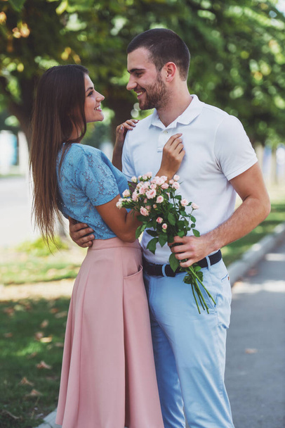 Amar pareja joven en una cita con flores en el parque - Foto, imagen