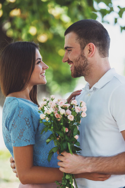 Kochająca młoda para na randce z kwiatami w parku - Zdjęcie, obraz