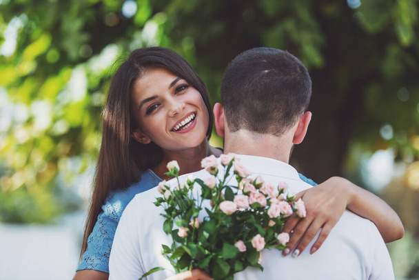 Amour jeune couple sur un rendez-vous avec des fleurs dans le parc - Photo, image