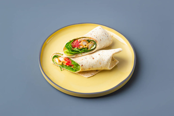 Pair of fresh wrap sandwiches with chicken and vegetables on yellow on grey plate trendy color - Foto, immagini