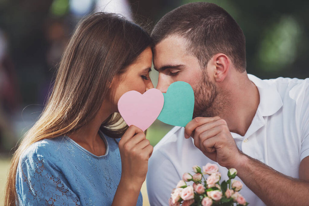 Amour jeune couple sur un rendez-vous avec des fleurs et avec un cadeau dans le parc - Photo, image