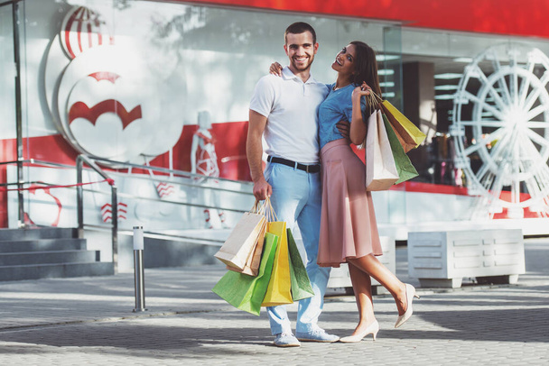 Liefdevolle jong koppel met zakken om te winkelen, wandelen naar de stad - Foto, afbeelding