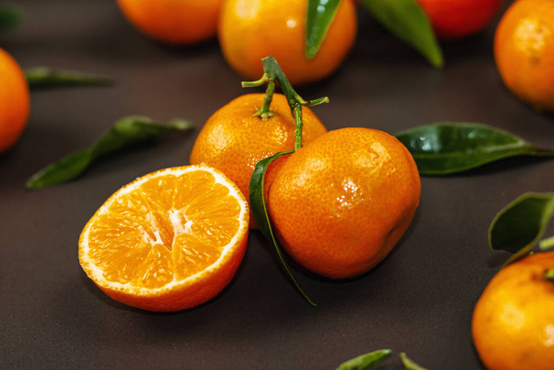 Tangerinky (pomeranče, mandarinky, klementinky, citrusové plody) s listy a jedlovými větvemi. Černý kámen pozadí, slavnostní byt ležel, zblízka - Fotografie, Obrázek