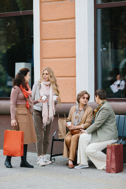 Ηλικιωμένες καλύτερες φίλες που διασκεδάζουν συζητώντας για ψώνια καθισμένες σε ένα παγκάκι στο δρόμο - Φωτογραφία, εικόνα