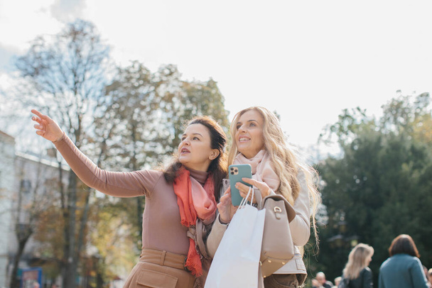 Senior female girlfriends discussing shopping while walking the city streets. - Foto, Bild