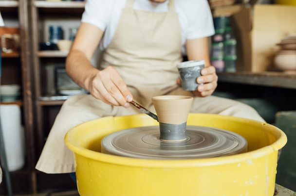 Hands of a potter. Potter making ceramic pot on the pottery wheel - Foto, imagen