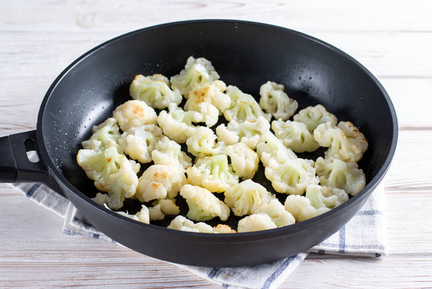 Ψητά κουνουπίδια στον ατμό σε τηγάνι, λαχανικά μαγειρέματος για υγιεινό χορτοφαγικό πιάτο, επιλεγμένη εστίαση, μικρό βάθος πεδίου - Φωτογραφία, εικόνα