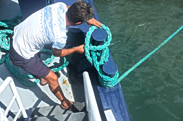 Fischer wickelt Seil auf Boot - Foto, Bild