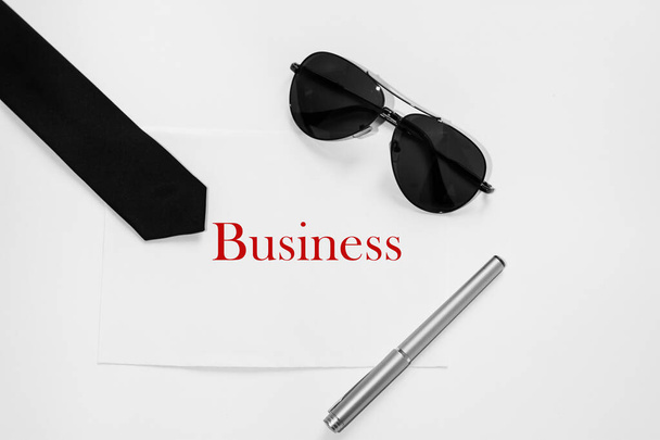 Czerwone słowo - Biznes na papierze biurowym obok okularów przeciwsłonecznych, krawatów i długopisów - Zdjęcie, obraz