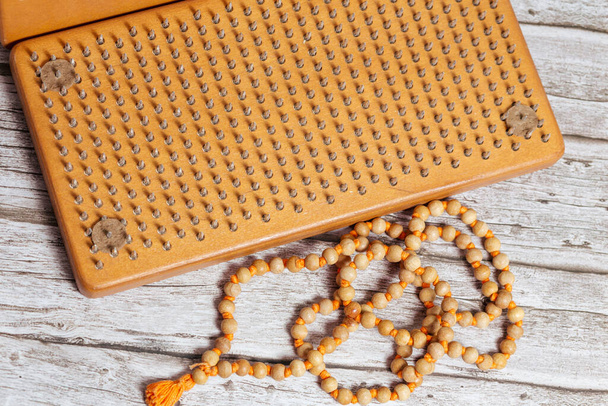 Rosaire bouddhiste tibétain, appelé mala ou japamala. Panneaux en bois brun Sadhu avec des clous pour le yoga et les pratiques spirituelles sur le fond gris. Le concept de méditation, debout sur les ongles, thérapie. - Photo, image