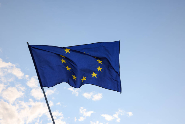 Σημαία της Ευρωπαϊκής Ένωσης που κυματίζει στον άνεμο πάνω από τον καταγάλανο ουρανό, σύμβολο του ευρωπαϊκού πατριωτισμού, χαμηλή γωνία, πλευρική άποψη - Φωτογραφία, εικόνα