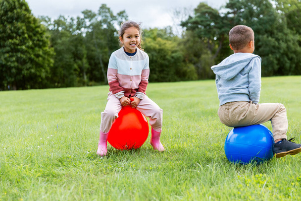 happy children bouncing on hopper balls at park - Фото, изображение