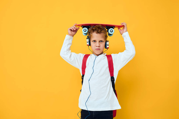 teenager with a red backpack wearing skateboard headphones - Fotó, kép