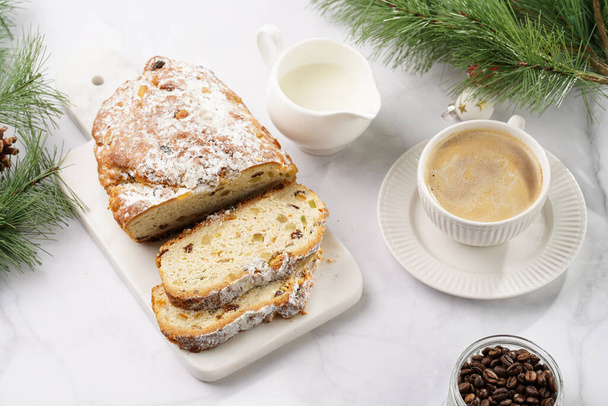 White porcelain cup with coffee cappuccino on a white saucer plate and christmas pastry stollen on a marble table - Photo, Image