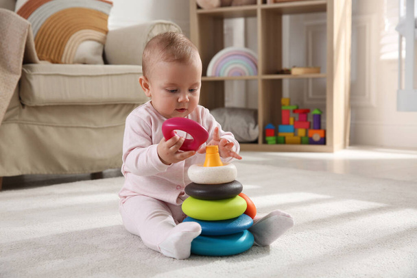 Cute baby girl playing with toy pyramid on floor at home - Фото, зображення