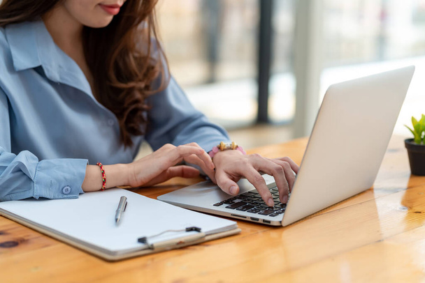 Primo piano della mano di una donna d'affari che digita usando un computer portatile in ufficio. - Foto, immagini