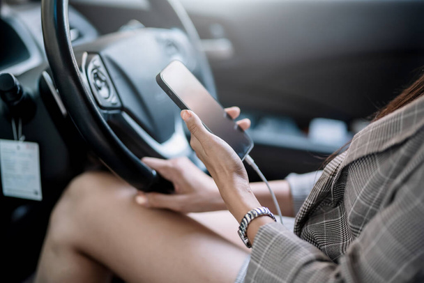 Közelkép fiatal nő kezét használja mobiltelefon az autóban. - Fotó, kép