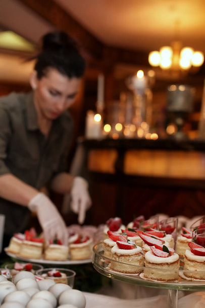 прикрасити святковий стіл солодощами і різноманітними солодкими закусками на тлі дівчини-кондитерки
 - Фото, зображення